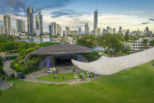 Aerial view of Cloud Play by Patrick Shearn of Poetic Kinetics suspended over the HOTA Outdoor Stage lawn, with guests gathering beneath and the Gold Coast city skyline in the background.