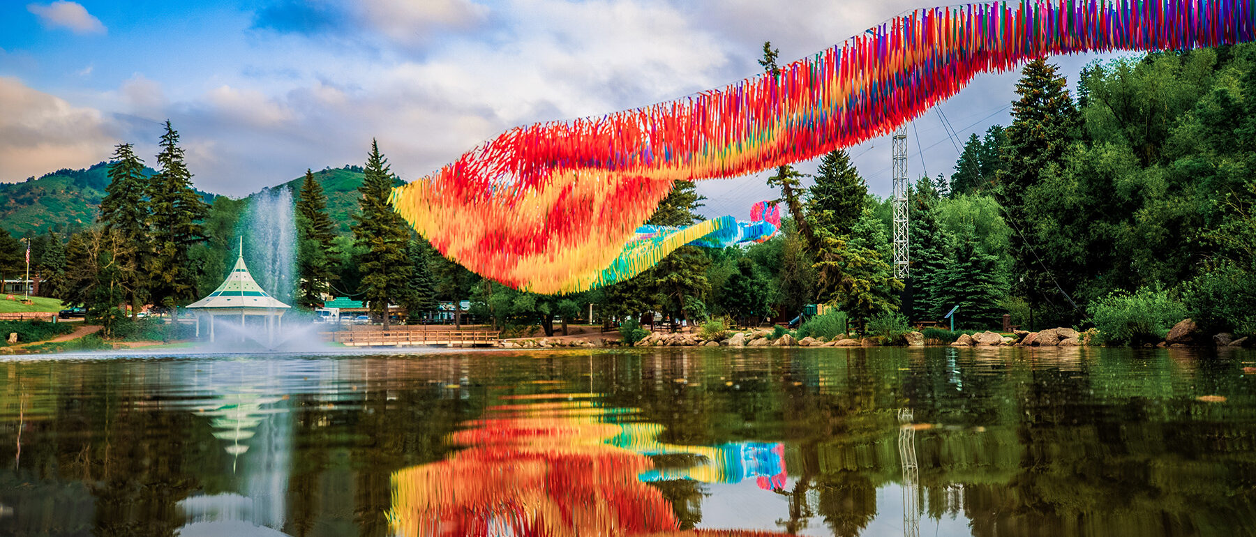 Off the Beaten Path art installation Green Mountain Falls reflecting in Gazebo Lake against mountain backdrop